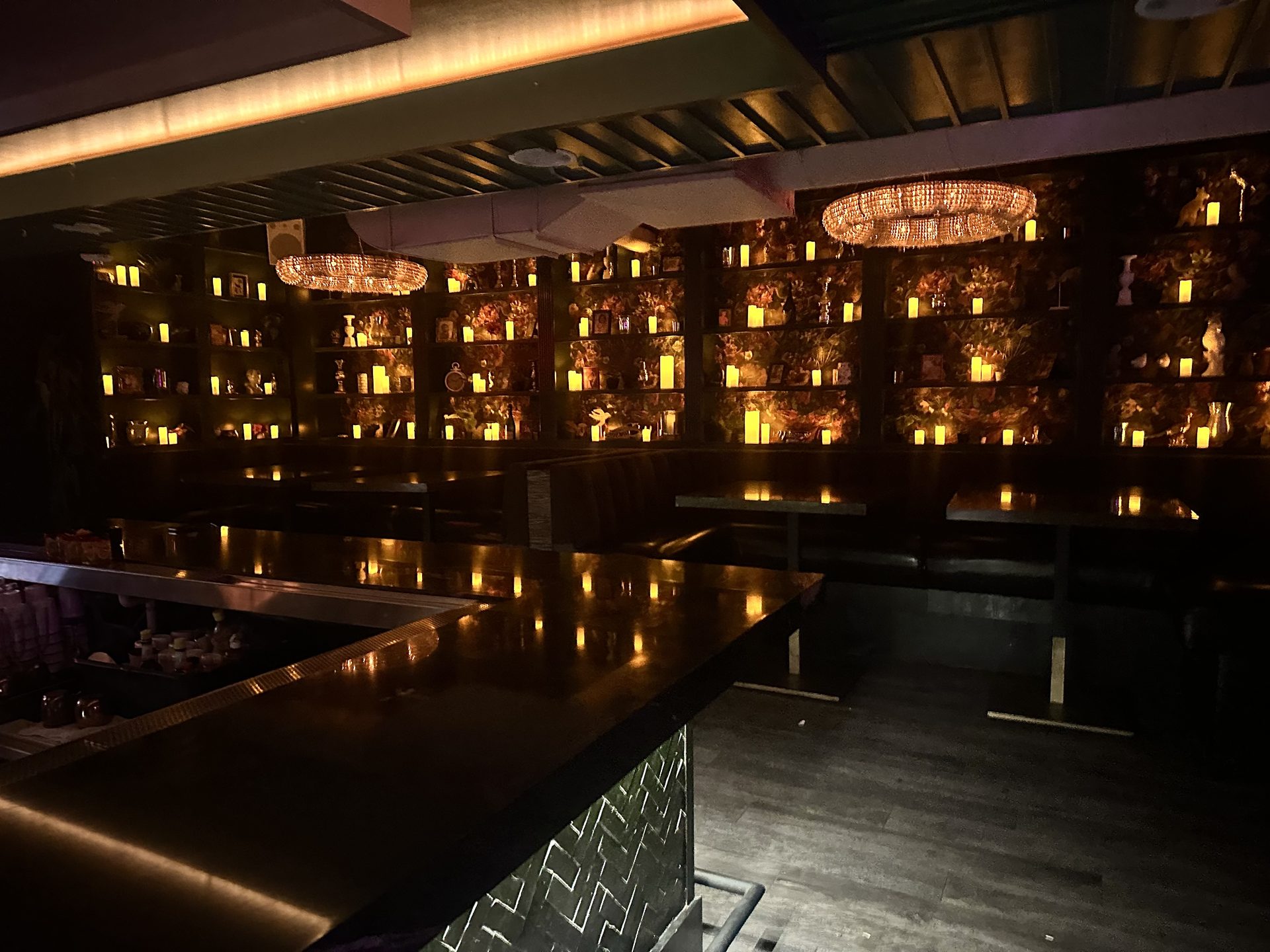 The candle-lit bar at Friends Only, dark wood and crystal chandeliers